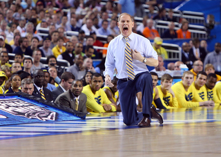 Head coach John Beilein of the Michigan Wolverines yells as he kneels on the sideline against the Syracuse Orange.