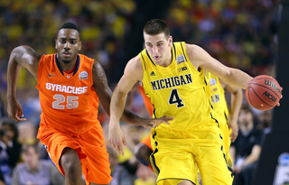 Mitch McGary #4 of the Michigan Wolverines takes the ball down the court against Rakeem Christmas #25.