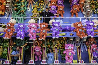 Energetic hosts of a game booth at The Great New York State fair encourage visitors to join a water gun competition to win one of the colorful plush prizes at the New York state fair. Winners could choose from teddy bears, sock monkeys and more.