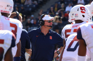 Shafer, donning a headset and visor, talks to his players on the sideline. 