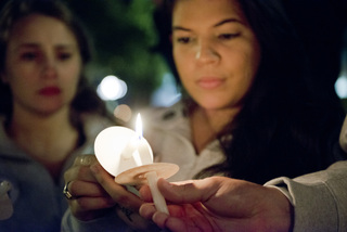 Alexandra Marie Figueroa, a senior dual major in anthropology and international relations and Remembrance Scholar, lights a candle at the Candle Light Vigil.