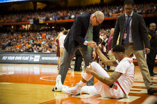 Trainer Brad Pike helps McCullough up. The freshman will be re-evaluated Monday, according to SU Athletics.